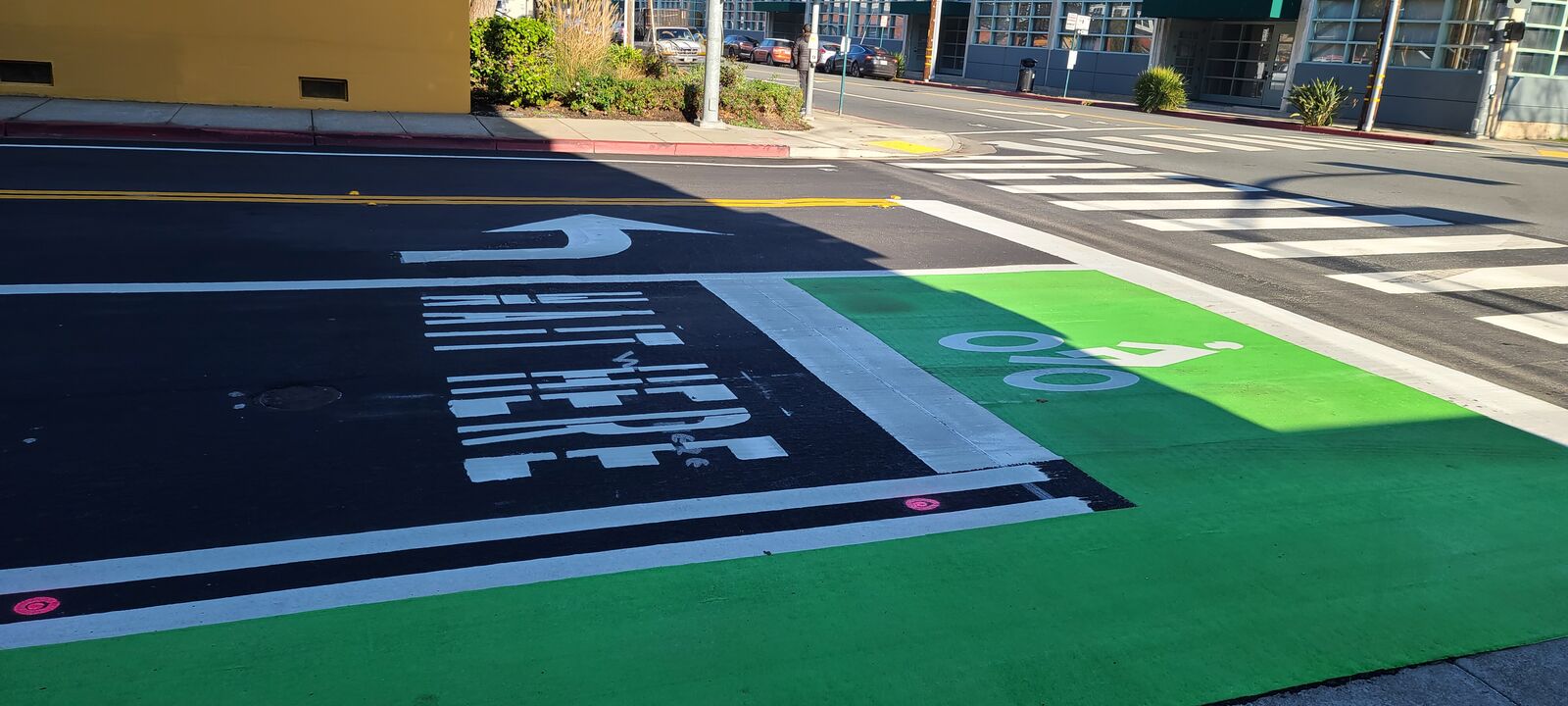 A green bike crossing painted through a crosswalk